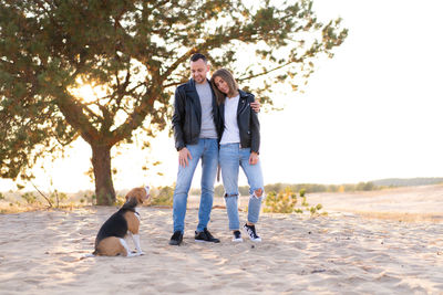 Couple standing with dog on beach