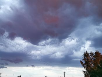 Low angle view of trees against dramatic sky