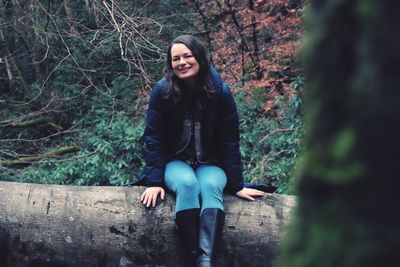 Portrait of young woman sitting in forest