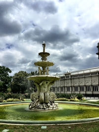 Fountain against cloudy sky