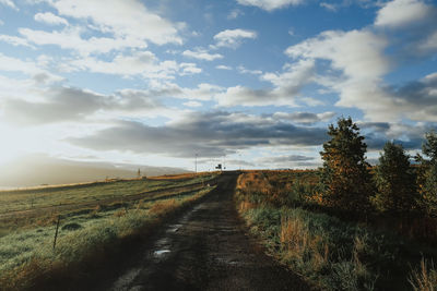 Road amidst field against sky