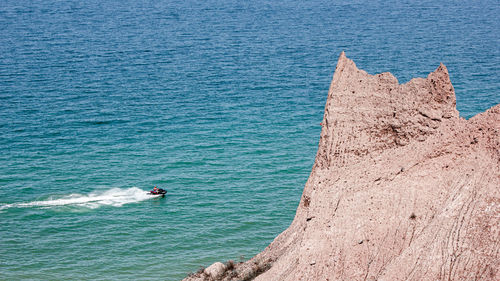 Jet skier in the water passing towering cliff