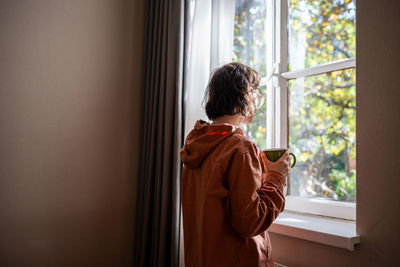 Rear view of woman standing at home