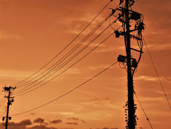 Low angle view of silhouette electricity pylon against sky during sunset