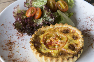 High angle view of savory pie with salad in plate