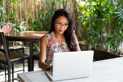 Woman looking away while sitting on table