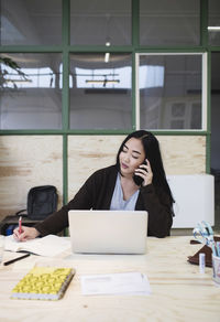 Woman using smart phone at desk in creative office