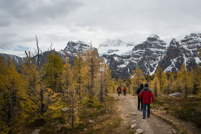 Rear view of people walking on snow covered mountain