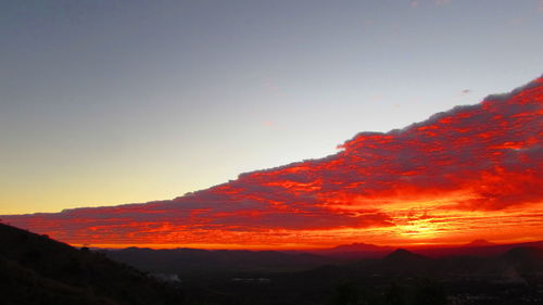 Scenic view of silhouette mountains against orange sky