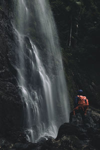 Rear view of person standing by waterfall at night