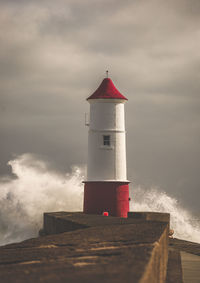 Lighthouse by sea against sky