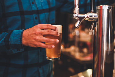 Midsection of man holding of beer glass