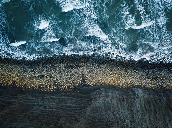 High angle view of waves rushing towards rocks