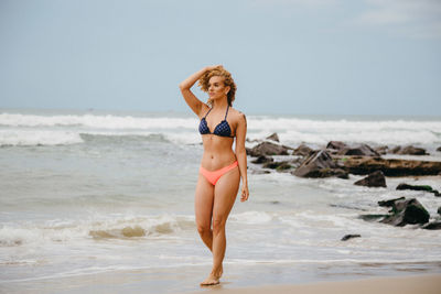 Full length of woman standing at beach against sky