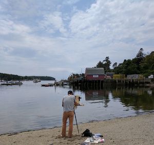 Rear view of man standing at beach against sky