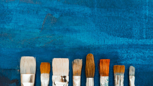 Directly above shot of paintbrushes on blue background