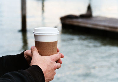 Cropped image of man holding disposable coffee cup