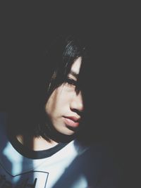 Close-up portrait of young woman against black background