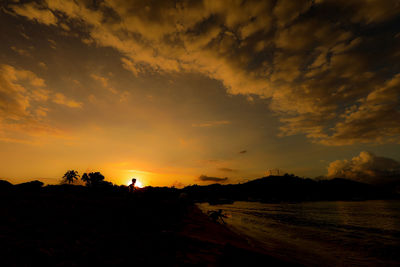 Silhouette people on beach against sky during sunset