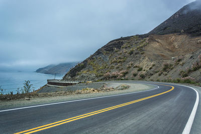 Road by mountain against sky