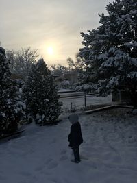 Rear view of person on snow covered field against sky
