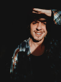 Portrait of smiling young man against black background