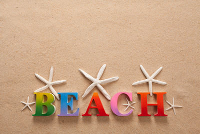 Directly above shot of beach text with seashells on sand at beach