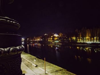 River by illuminated buildings in city at night