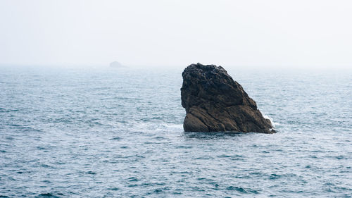 Scenic view of rock formation in sea against clear sky