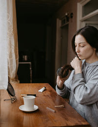 Side view of young woman sitting at home