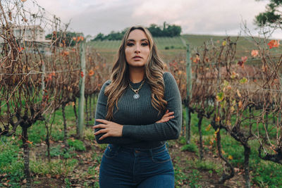 Portrait of beautiful young woman standing on field