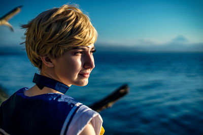 Side view of woman looking at sea against sky