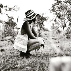 Side view of young woman crouching on field