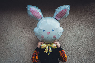 Person wearing easter bunny mask against wall