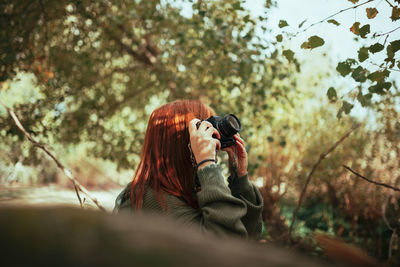 Woman holding camera while standing during winter