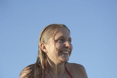 Portrait of smiling young woman against clear sky