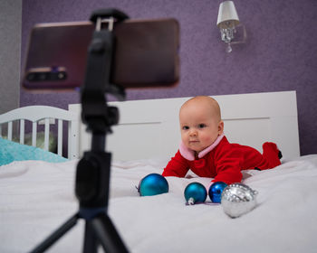 Cute baby looking at mobile phone mounted on tripod