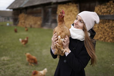 Woman holding bird standing against blurred background