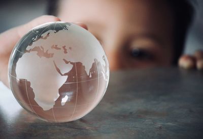 Close-up of boy holding glass globe on table