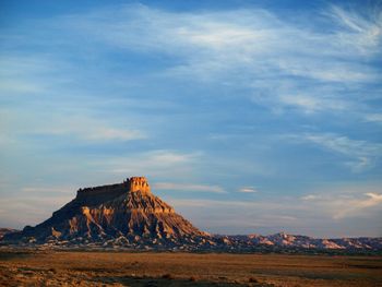 Rock formations on landscape against cloudy sky