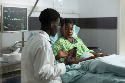 Rear view of man using laptop on bed