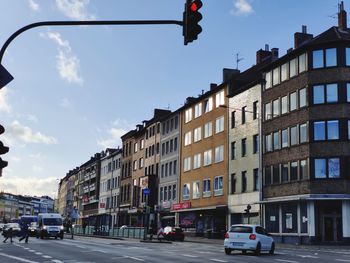 Cars on street by buildings against sky in city