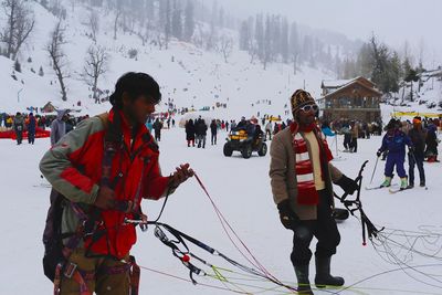 People on snow covered field against mountain