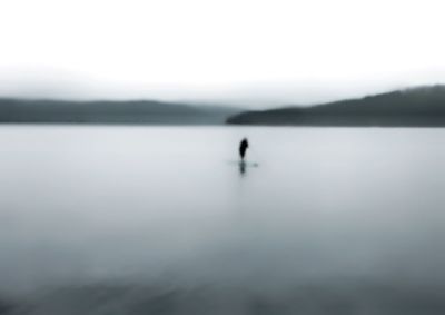 Silhouette man in lake against sky