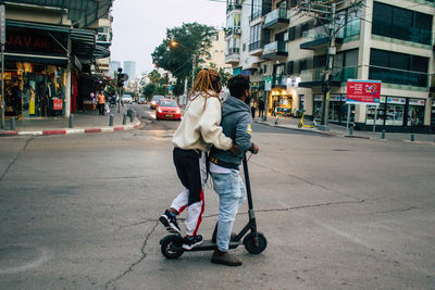 Rear view of people riding motorcycle on road