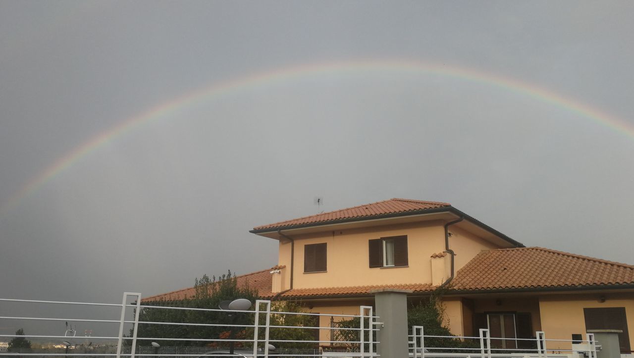 LOW ANGLE VIEW OF RAINBOW OVER BUILDING AND HOUSES AGAINST SKY