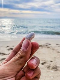 Close-up of hand holding sand on beach