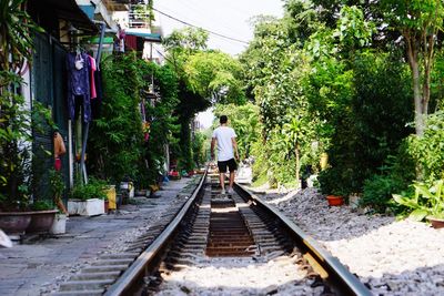 Rear view of man walking on railroad track