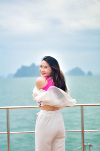 Young woman standing against sea