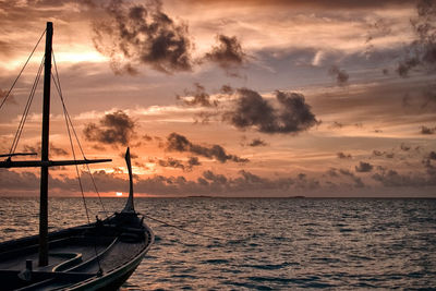 Boat moored in sea against sky during sunset